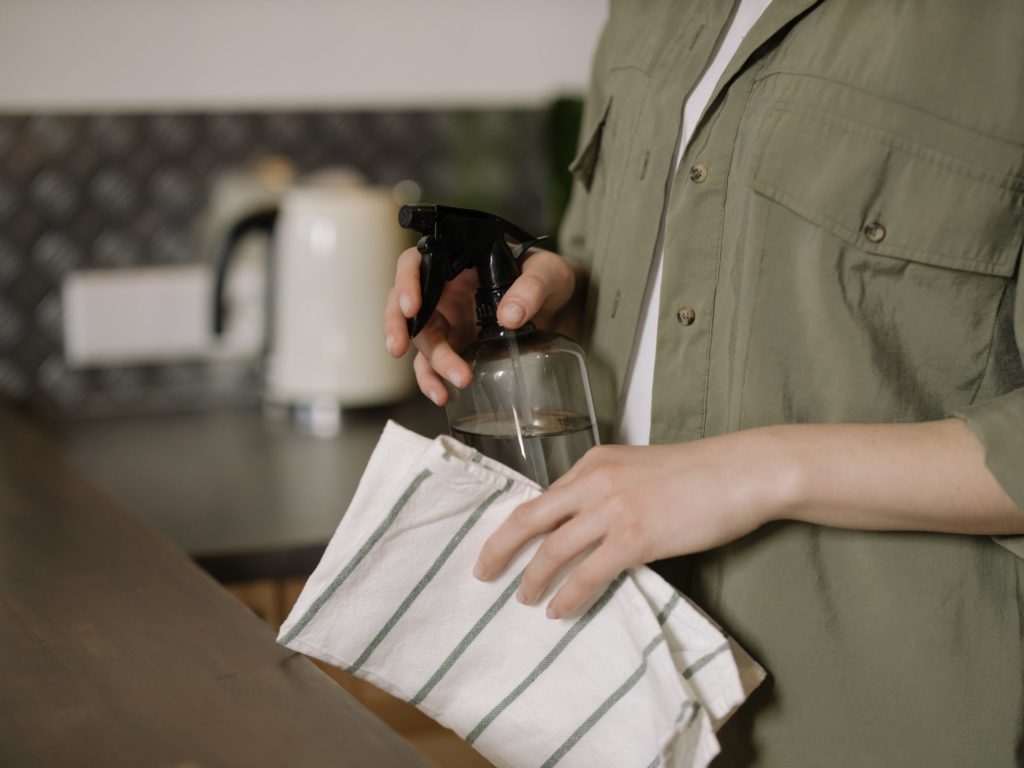 Person with spray bottle and dish cloth