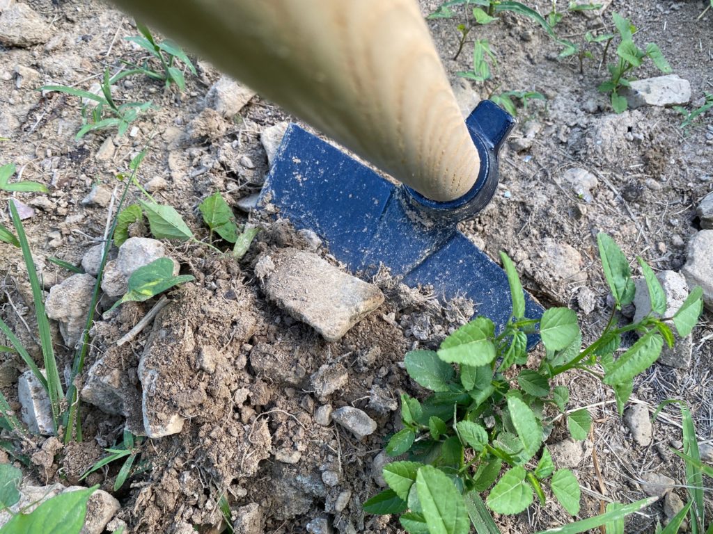 The pointed hoe scooping up rocks.