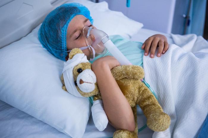 Kid in a hospital bed with a breathing mask